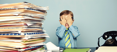 Stacks of worthless stock tax paperwork sit on a desk beside a child in button up shirt and tie holding his face in his hands in frustration.