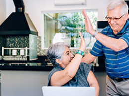 An older couple high fives each other in their home office setting as they take advantage of an low income year