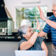 An older couple high fives each other in their home office setting as they take advantage of an low income year
