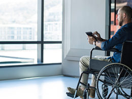 Man in wheelchair in a commercial building looks out a window