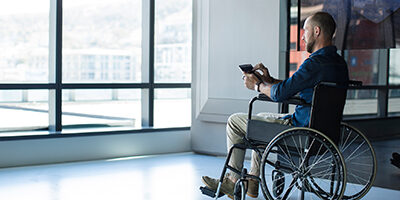 Man in wheelchair in a commercial building looks out a window