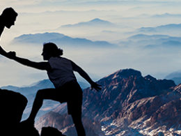 one person standing on a mountain helping another person up. Nissen and Associates Tax and Accounting