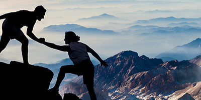 one person standing on a mountain helping another person up. Nissen and Associates Tax and Accounting