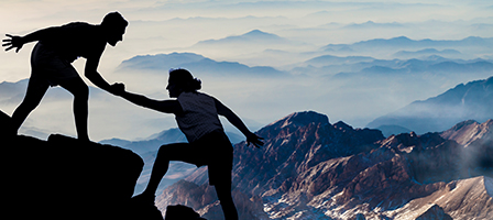 one person standing on a mountain helping another person up. Nissen and Associates Tax and Accounting