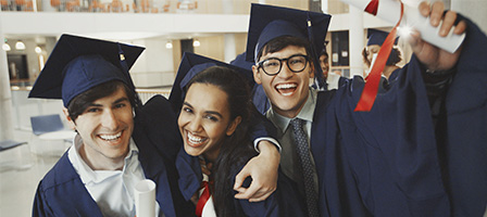 Three jovial students in graduation cap and gown. clutching their diplomas, celebrate the above The Line Education Tax Deduction Reinstatment