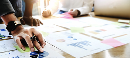 Two people sit at a desk discussing the THE DIFFERENCE BETWEEN AN AUDIT, A REVIEW, AND A COMPILATION