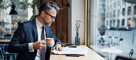 a man dressed in a business suit drinks coffee and reviews the Highlights of recent Tax law changes in a public coffee shop