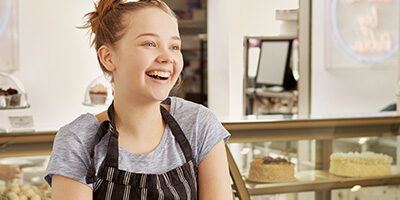 New Twist For Kiddie Tax With A Refund Opportunity A young female child is laughing as she stands in a kitchen with an apron on.