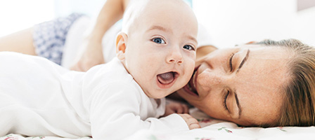 A mother and her baby lay down on a bed excited that the Childbirth And Adoption Penalty Exception was Added