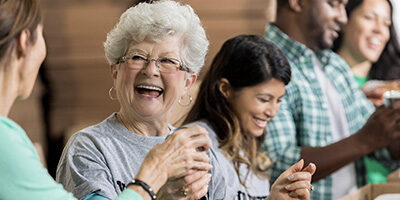 A elderly woman laughs as she talks to a friend about the New Twist Added To The IRA-To-Charity Provision