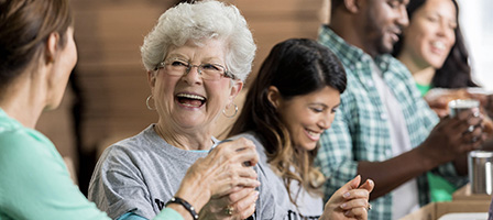 A elderly woman laughs as she talks to a friend about the New Twist Added To The IRA-To-Charity Provision