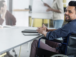 A man in a wheelchair sits at a desk reading about how Congress Extends Employers' Hiring Tax Credit For Another Year