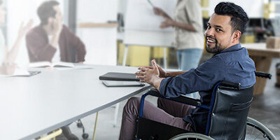 A man in a wheelchair sits at a desk reading about how Congress Extends Employers' Hiring Tax Credit For Another Year