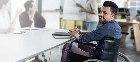 A man in a wheelchair sits at a desk reading about how Congress Extends Employers' Hiring Tax Credit For Another Year