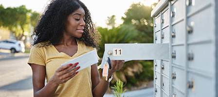 A woman stands at her mailbox holding an IRS letter wondering IRS if it's a Tax Scam Or Something You Need To Address?