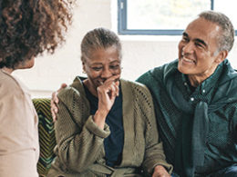 GOOD IRA NEWS FOR RETIREES, a couple sits on a couch laughing to themselves and looking happy