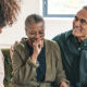 GOOD IRA NEWS FOR RETIREES, a couple sits on a couch laughing to themselves and looking happy