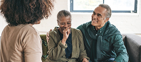 GOOD IRA NEWS FOR RETIREES, a couple sits on a couch laughing to themselves and looking happy