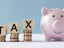 What Does A Tax Deduction Save You? T A X is spelled out in scrabble tile letters next to a small pink ceramic classic piggy bank