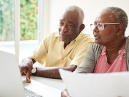 Running Low on Money? Congress Has Made It Easier for You to Tap Your Retirement Savings. A couple sits in front of a laptop smiling