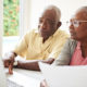 Running Low on Money? Congress Has Made It Easier for You to Tap Your Retirement Savings. A couple sits in front of a laptop smiling