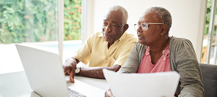 Running Low on Money? Congress Has Made It Easier for You to Tap Your Retirement Savings. A couple sits in front of a laptop smiling