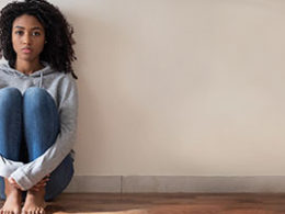 How Can I File for Unemployment in The United States? A woman sits on the floor, back against the wall, alone.