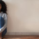 How Can I File for Unemployment in The United States? A woman sits on the floor, back against the wall, alone.