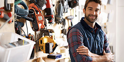 Self-Employed and Independent Contractors Now Qualify for Unemployment Benefits. A man in a flannel shirt stands crossing his arms in a landscaping shop.