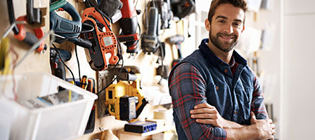 Self-Employed and Independent Contractors Now Qualify for Unemployment Benefits. A man in a flannel shirt stands crossing his arms in a landscaping shop.