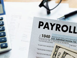 Employers Can Defer Payroll Taxes, show a calculator, PAYROLL sheet and a pair of glasses sitting on a desk.