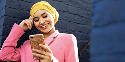 Track Your Economic Impact Payment in The New IRS Portal. A woman looks down engaged with her phone.