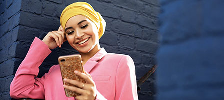 Track Your Economic Impact Payment in The New IRS Portal. A woman looks down engaged with her phone.