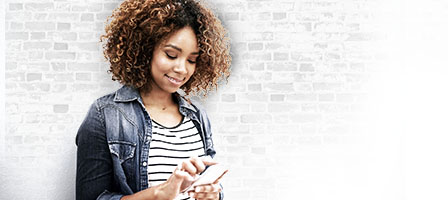 The IRS Provides Online Tools for Recovery Rebates, a woman stands against a wall, checking her phone with a smile