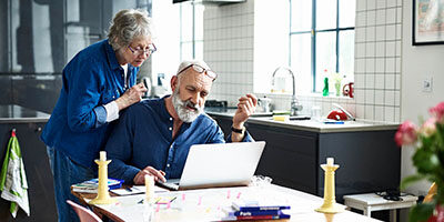 Did You Take Your 2020 RMD Too Soon? An elderly woman peers through her glasses, looking at a laptop screen, while her husband is typing.