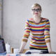 7 Tips to Keep Your Business Afloat During Covid-19 - A poround female business owner stands behind her office desk, smiling