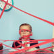 Government Keeping Your Refund? A child dressed in a suit sits at a desk completely surrounded and covered in red tape