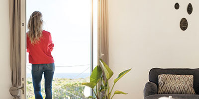 Wealthy Taxpayers May Want to Strategize for Potential Tax Increases, a woman stands by a window of a classy home looking out at the view.