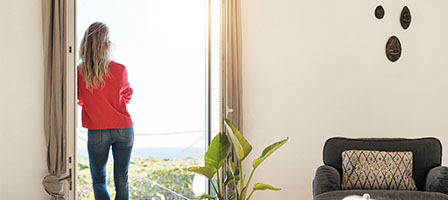 Wealthy Taxpayers May Want to Strategize for Potential Tax Increases, a woman stands by a window of a classy home looking out at the view.