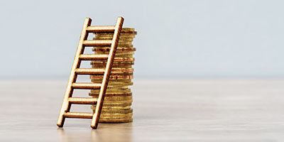 IRS Extends the Opportunity to Defer Capital Gains. A ladder leans against a stack of gold coins