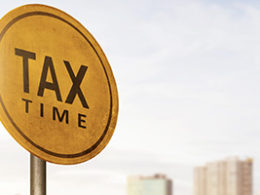 October's Extended Due Date is Almost Here. Scott Nissen at Nissen and Associates can help you with your taxes. A round sign proclaiming Tax Time on a metal pole with a blurred cityscape background