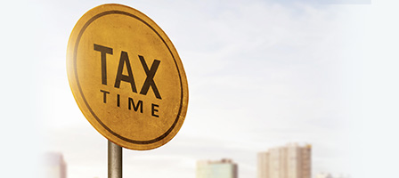 October's Extended Due Date is Almost Here. Scott Nissen at Nissen and Associates can help you with your taxes. A round sign proclaiming Tax Time on a metal pole with a blurred cityscape background