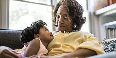 Keeping Your Designated IRA Beneficiary Current Is Important, A older woman warmly smiles down at her granddaughter.