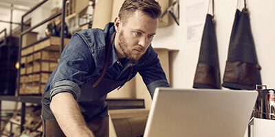 Ready for the 1099-NEC? A man stands over a laptop with a concerned look on his face