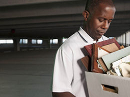 Tax Consequences of Losing Your Job, a sad faced person walks away with a box full of personal effects in a car garage.