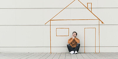 Unable to Keep Up with Your Home Mortgage Payments? A man sits on the ground outside a stick drawing of a house.