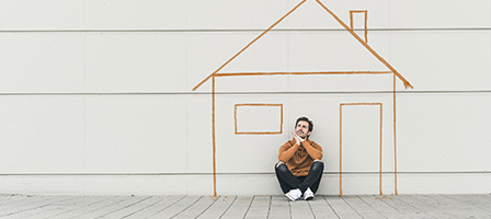 Unable to Keep Up with Your Home Mortgage Payments? A man sits on the ground outside a stick drawing of a house.