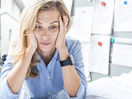 What Happens If I Missed the October 15th Tax Extension Deadline? A woman with tax problems sits holding her head in her hands with an overwhelmed expression on her face.