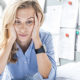 What Happens If I Missed the October 15th Tax Extension Deadline? A woman with tax problems sits holding her head in her hands with an overwhelmed expression on her face.