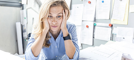 What Happens If I Missed the October 15th Tax Extension Deadline? A woman with tax problems sits holding her head in her hands with an overwhelmed expression on her face.